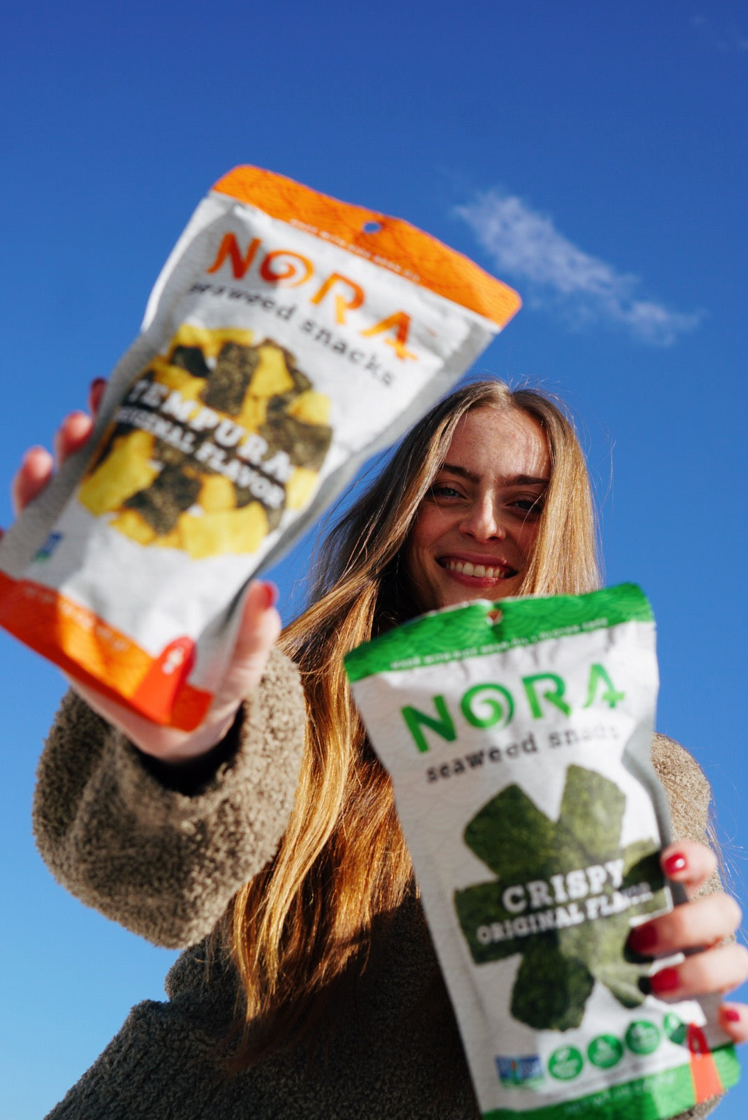 Young woman holding up two bags of Nora Seaweed Snacks